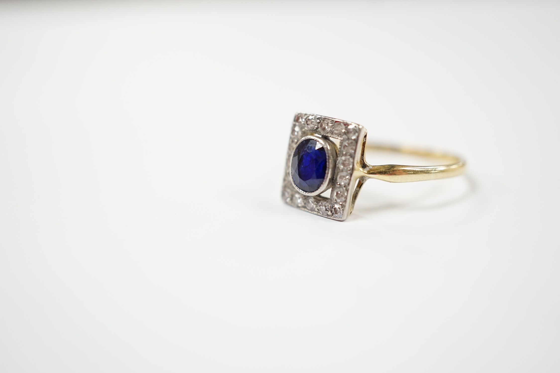 A yellow metal, sapphire and diamond cluster set tablet ring, size P, gross weight 2.3 grams.